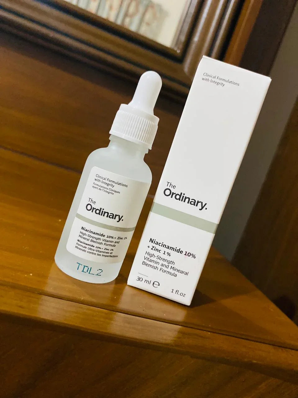 The Ordinary Niacinamide 10% + Zinc 1% serum bottle and box on wooden surface, skincare product