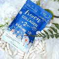 Frozen Collagen 2 in 1 Whitening X10 capsules with snowman design, surrounded by white flowers and pills